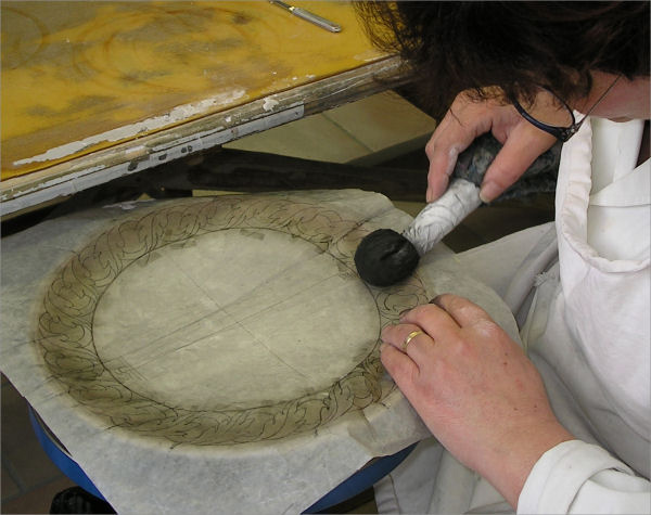 A Deruta ceramic artisan is using the "spolvero" on a dinner plate before starting painting