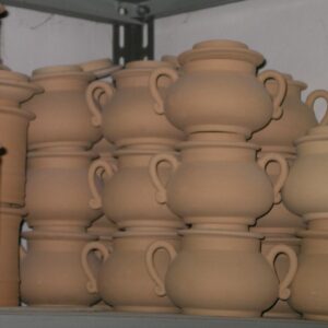 A stack of unglazed sugar bowls in a Deruta artisan workshop