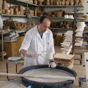 A Deruta artisan is dipping the unglazed ceramic mug in liquid glaze